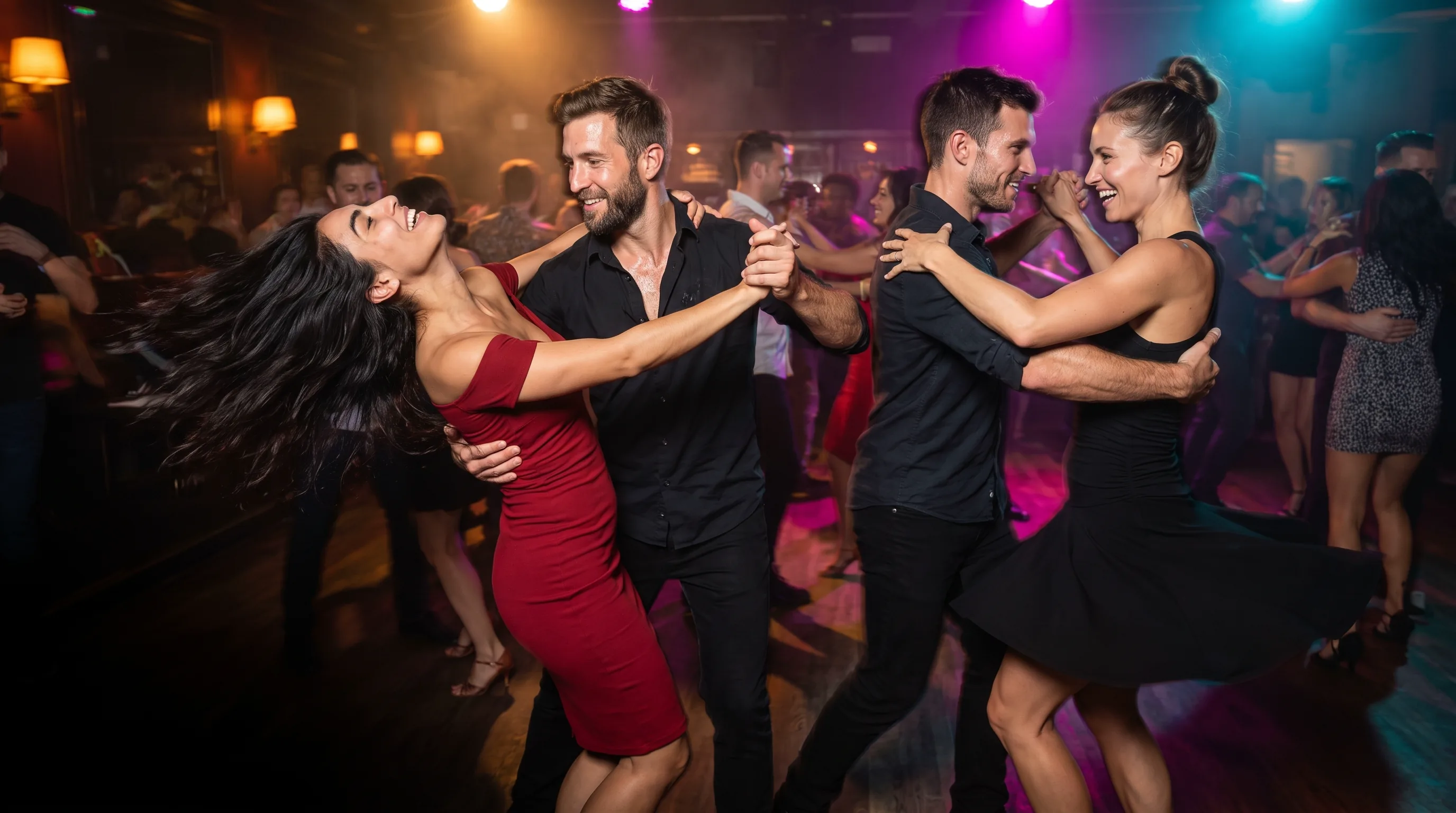 Four friends salsa dancing as two couples on a crowded dance floor at night, one of them spun out mid-turn with her hair flying.